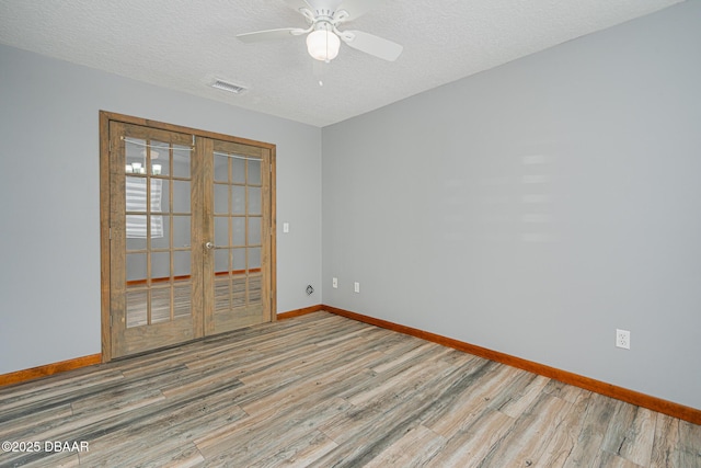 unfurnished room with hardwood / wood-style flooring, a textured ceiling, and french doors