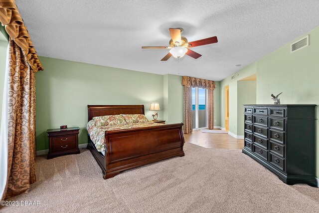 carpeted bedroom featuring a textured ceiling, ceiling fan, and baseboards