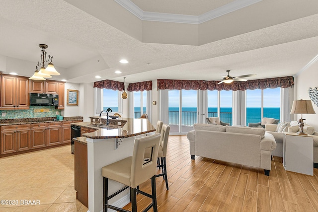 kitchen featuring black appliances, crown molding, a breakfast bar, a water view, and a sink
