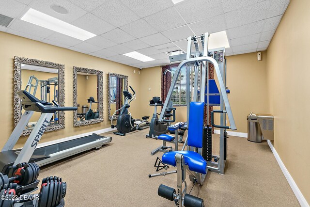 exercise room featuring a drop ceiling and baseboards