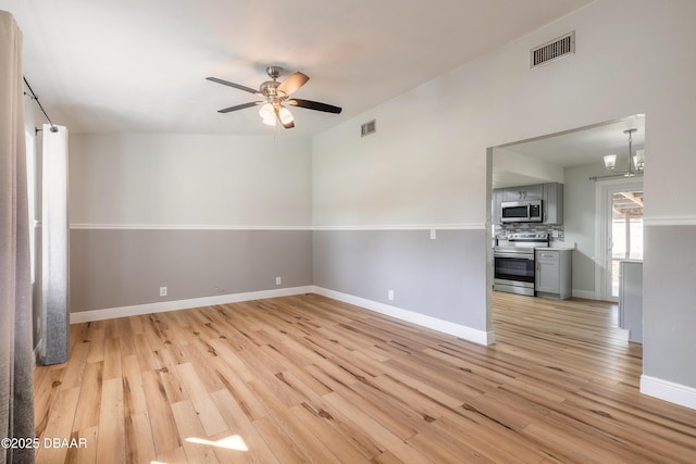 spare room with ceiling fan with notable chandelier and light hardwood / wood-style floors