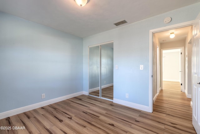 unfurnished bedroom featuring light wood-type flooring and a closet