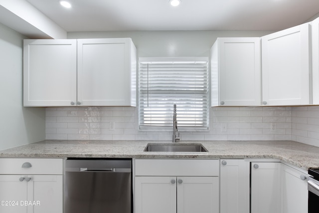 kitchen featuring tasteful backsplash, light stone counters, white cabinetry, sink, and stainless steel dishwasher