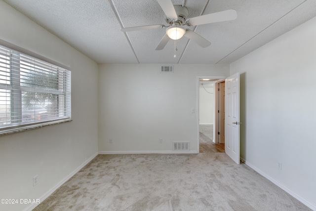 carpeted empty room with ceiling fan and a textured ceiling