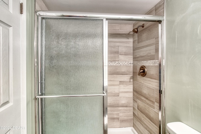 bathroom featuring toilet and an enclosed shower