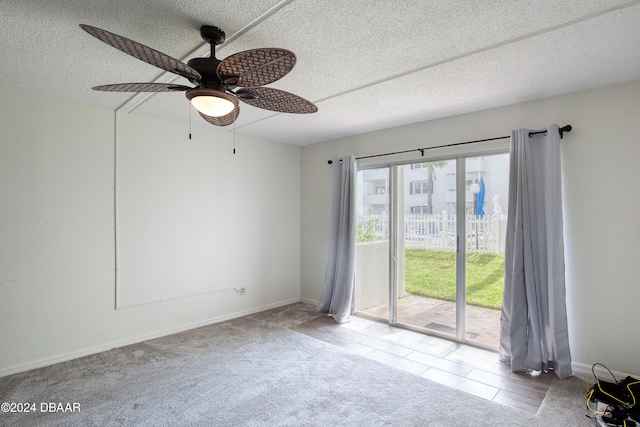 carpeted empty room featuring ceiling fan and a textured ceiling