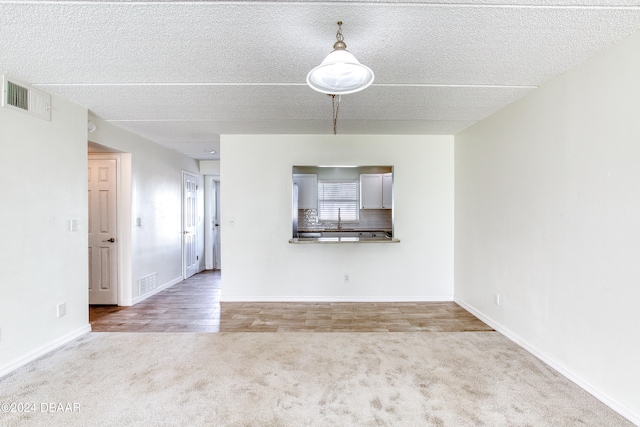 unfurnished living room featuring light hardwood / wood-style floors, a textured ceiling, and sink