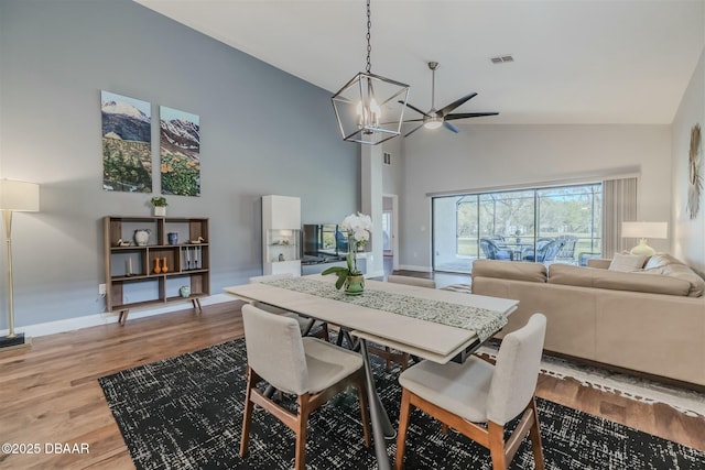 dining room featuring high vaulted ceiling, hardwood / wood-style floors, and a notable chandelier