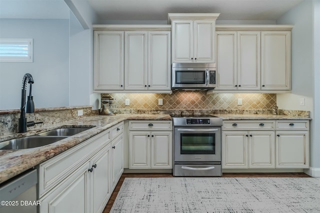 kitchen with decorative backsplash, stainless steel appliances, light stone countertops, and sink