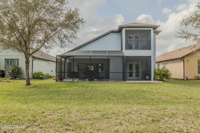 rear view of house featuring a yard, glass enclosure, and a patio