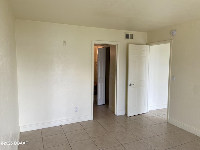 unfurnished room featuring light tile patterned floors, baseboards, and visible vents