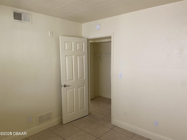 unfurnished bedroom with a closet, light tile patterned floors, baseboards, and visible vents