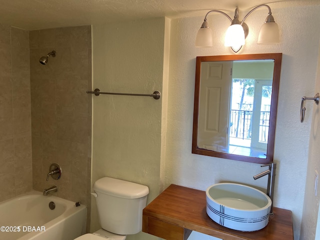 bathroom with a sink, toilet, shower / tub combination, and a textured wall
