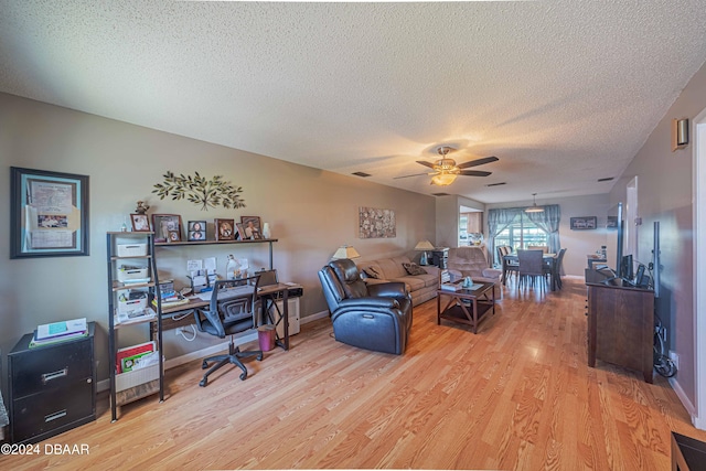 living room with ceiling fan, a textured ceiling, and light wood-type flooring