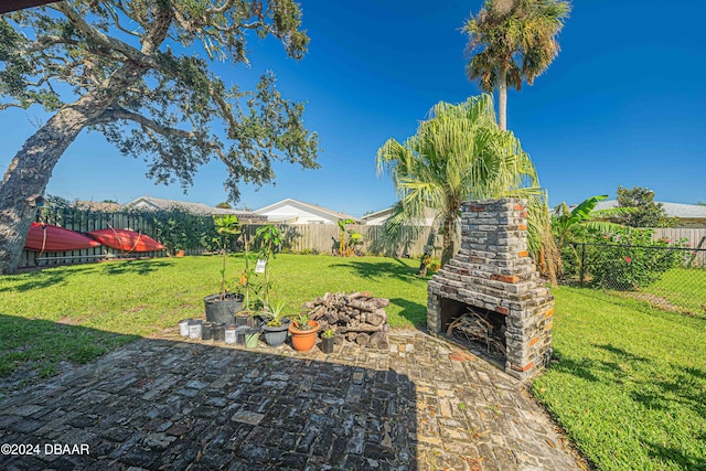 view of yard featuring an outdoor fireplace and a patio area