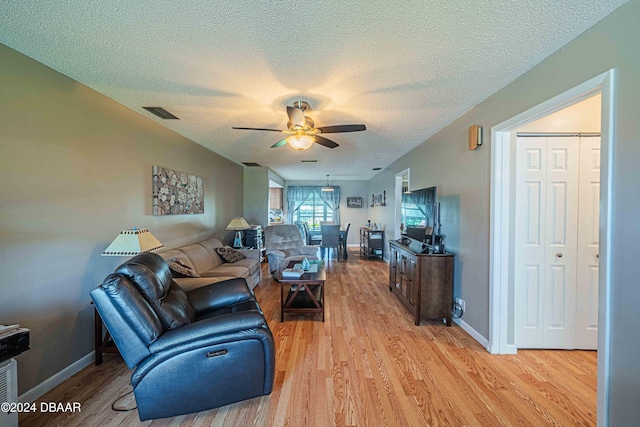 living room featuring ceiling fan, a textured ceiling, and light wood-type flooring