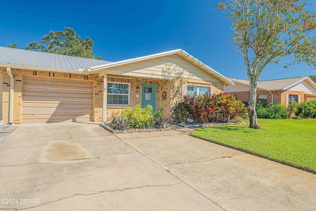 ranch-style house with driveway, a front lawn, a garage, brick siding, and metal roof