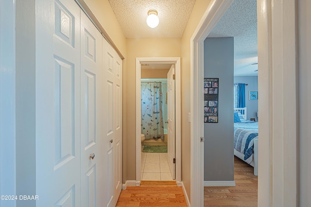 hallway featuring light wood-type flooring and a textured ceiling