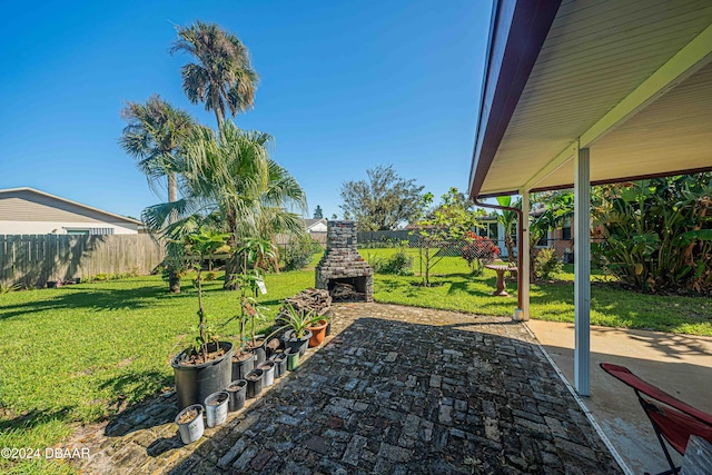 view of yard featuring a patio and an outdoor stone fireplace