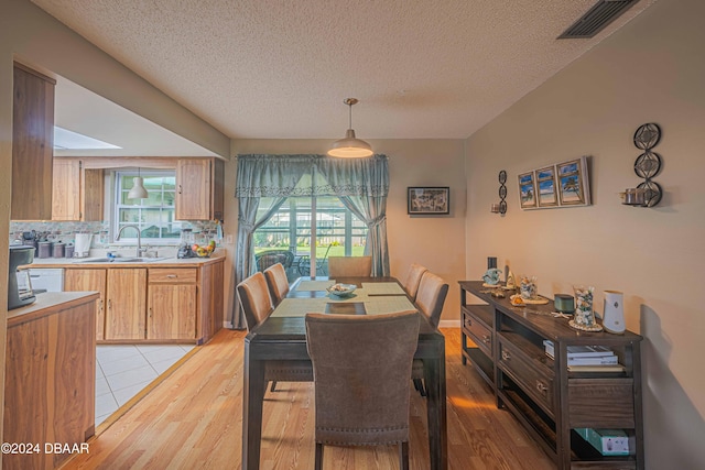 dining room featuring a textured ceiling, sink, and light wood-type flooring