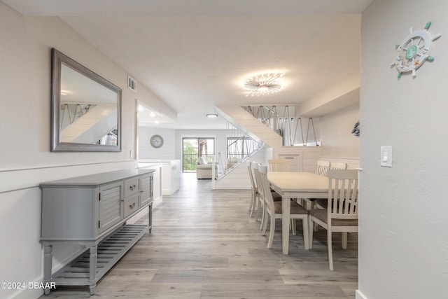 dining area featuring stairs, light wood-style flooring, and visible vents