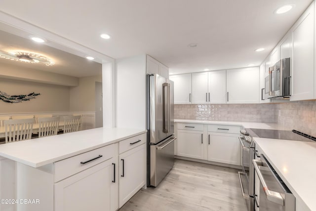 kitchen with stainless steel appliances, white cabinets, light countertops, and backsplash