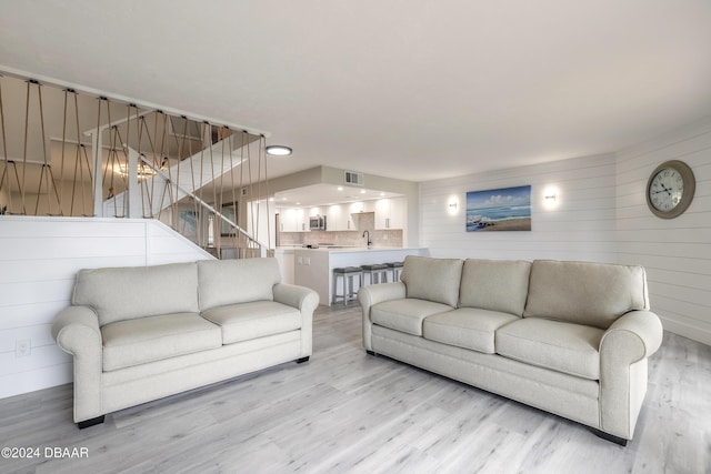 living area featuring stairs, light wood-type flooring, and visible vents