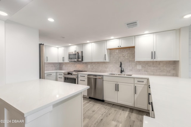 kitchen featuring a peninsula, white cabinetry, appliances with stainless steel finishes, and light countertops