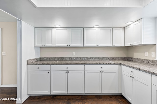 kitchen with light stone countertops, dark hardwood / wood-style flooring, and white cabinets