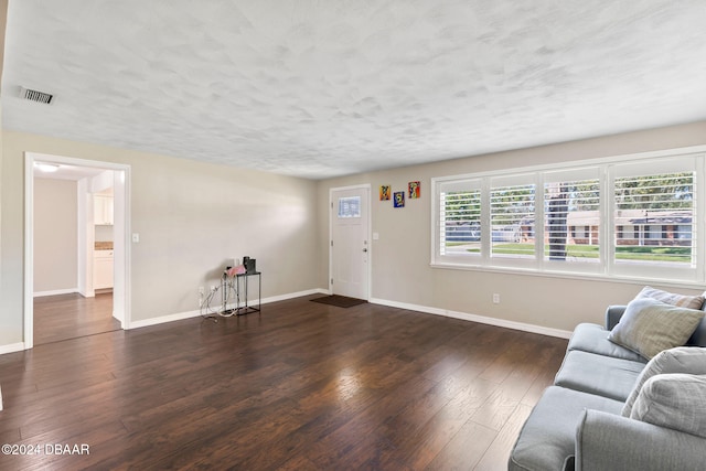 unfurnished living room featuring a textured ceiling and dark wood-type flooring