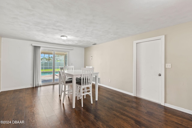 dining room featuring a textured ceiling and dark hardwood / wood-style floors