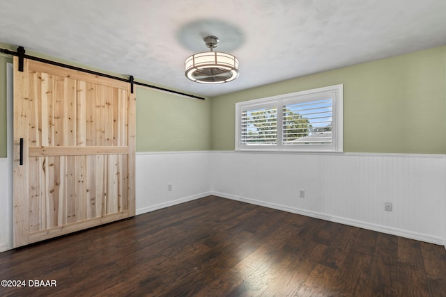 spare room with wood walls, a barn door, and dark hardwood / wood-style flooring