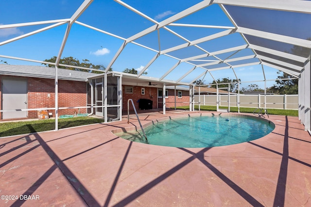 view of pool with glass enclosure and a patio