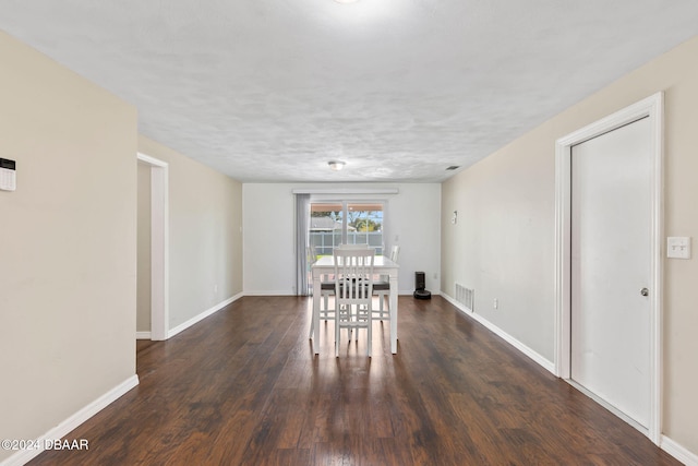 unfurnished dining area with dark wood-type flooring and a textured ceiling