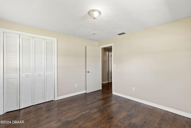 unfurnished bedroom with dark hardwood / wood-style floors and a closet