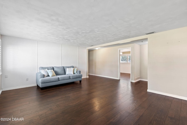 living room with a textured ceiling and dark hardwood / wood-style floors