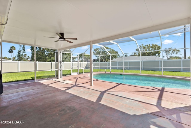 view of pool featuring a lawn, glass enclosure, ceiling fan, and a patio