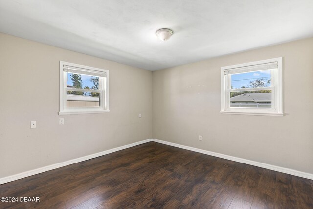 unfurnished room featuring plenty of natural light and dark wood-type flooring