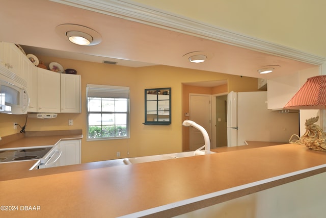 kitchen with kitchen peninsula, white appliances, and white cabinetry