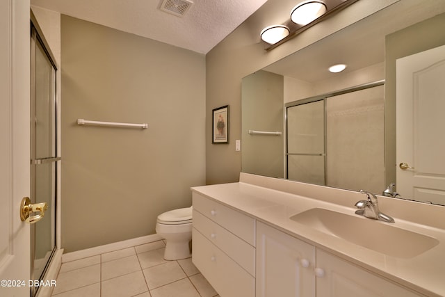 bathroom with tile patterned flooring, vanity, a shower with shower door, and a textured ceiling