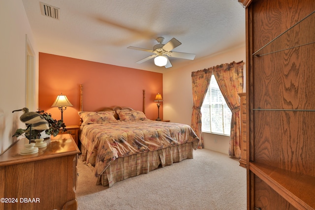 carpeted bedroom with ceiling fan and a textured ceiling