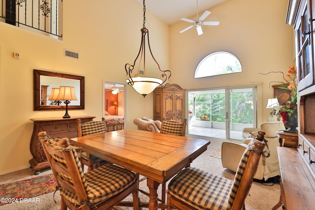 carpeted dining room with ceiling fan and high vaulted ceiling