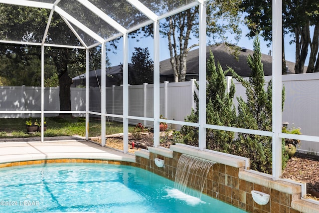 view of pool with pool water feature, glass enclosure, and a patio area