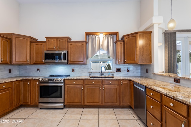 kitchen with appliances with stainless steel finishes, tasteful backsplash, sink, light tile patterned floors, and hanging light fixtures