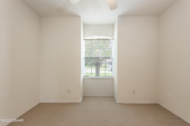 carpeted spare room featuring ceiling fan