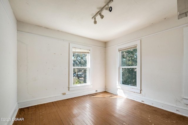 empty room with hardwood / wood-style floors and rail lighting