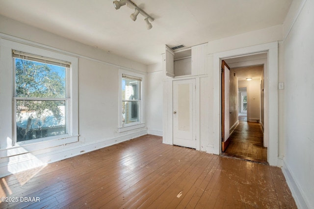 spare room featuring dark hardwood / wood-style floors and track lighting