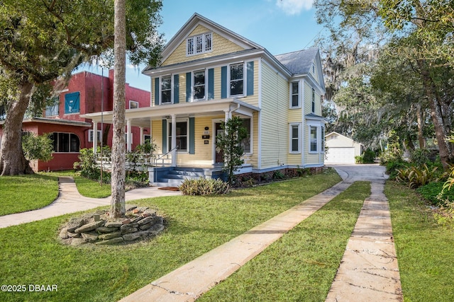 view of front facade featuring a garage, an outbuilding, covered porch, and a front lawn