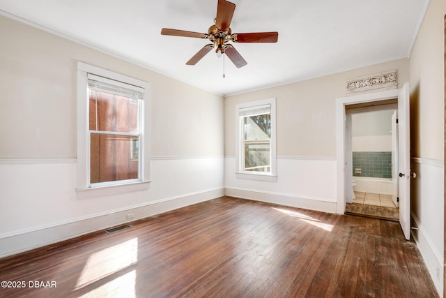 empty room with crown molding, dark wood-type flooring, and ceiling fan