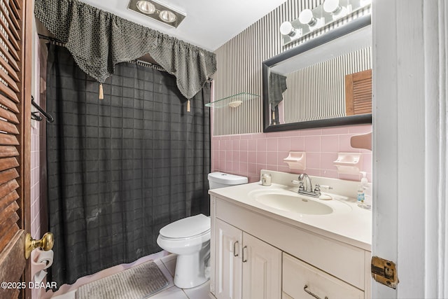 bathroom featuring curtained shower, tile walls, vanity, toilet, and tile patterned floors